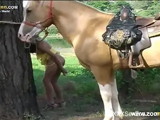 Latina with a ponytail fucks herself in front of a horse