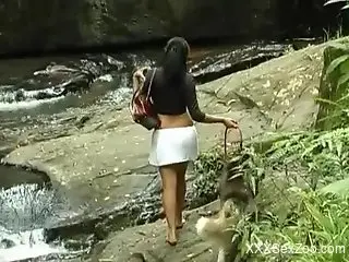 Stunning brunette fucks a dog by a waterfall